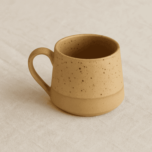 Χειροποίητη κεραμική κούπα με στικτή υφή πάνω σε γήινο